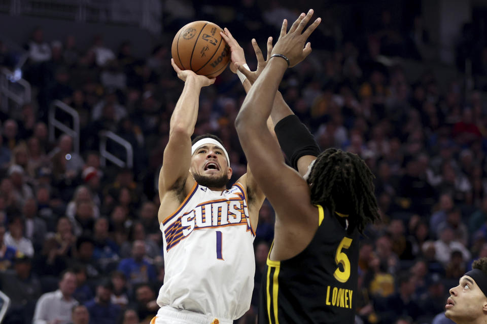 Phoenix Suns guard Devin Booker (1) shoots against Golden State Warriors forward Kevon Looney (5) during the first half of an NBA basketball game in San Francisco, Saturday, Feb. 10, 2024. (AP Photo/Jed Jacobsohn)