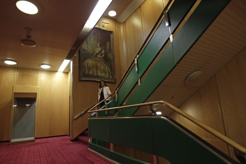 Leili Gerami, Queen Elizabeth 2 project director, walks down the stairs under a painting of Queen Elizabeth II, as Istithmar World, the Dubai state investment company that owns the ship, outlined plans Monday to turn the retired cruise liner into a 300-room hotel, ending years of speculation about its fate, in Port Rashid, Dubai, United Arab Emirates, Monday, July 2, 2012. Britain's Queen Elizabeth II launched the QE2 in 1967. (AP Photo/Kamran Jebreili)