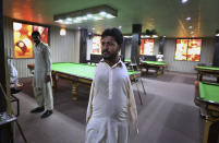 Mohammad Ikram, who play snooker with his chin, walks at a local snooker club in Samundri town, Pakistan, Sunday, Oct. 25, 2020. Ikram, 32, was born without arms, but everyone simply admires his snooker skills when he hits the cue ball with his chin and pots a colored ball on a snooker table. He lives in a remote rural town of Punjab province and his physical disability doesn't come in his way to fulfill his childhood dream of playing the game of snooker. (AP Photo/Anjum Naveed)