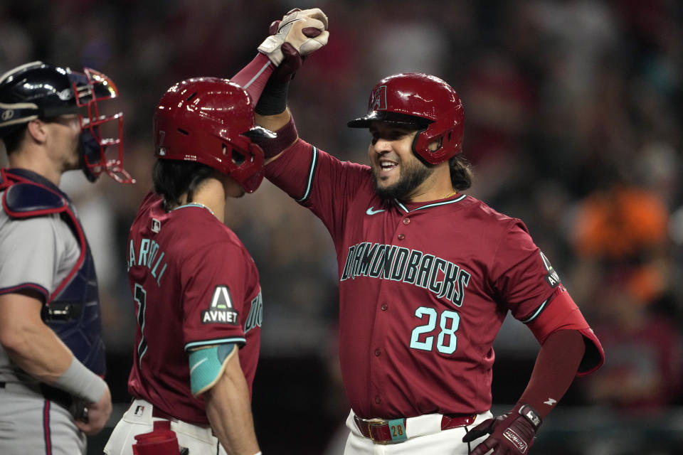 Arizona Diamondbacks' Eugenio Suárez celebrates his solo home run during the fifth inning of a baseball game against the Atlanta Braves with teammate Corbin Carroll, left, Thursday, July 11, 2024, in Phoenix. (AP Photo/Matt York)