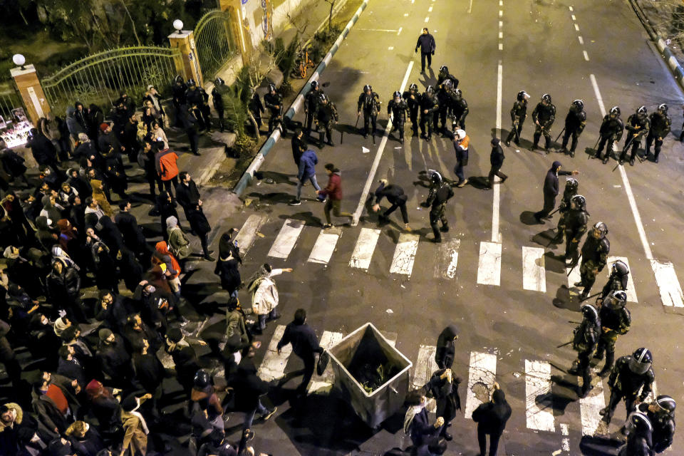 In this photograph taken Saturday, Jan. 11, 2020, Iranian police officers take position while protesters gather in front of Amir Kabir University in Tehran, Iran, to remember victims of a Ukrainian airplane shot down by an Iranian missile. On Monday, Jan. 13, 2020, online videos purported to show that Iranian security forces fired both live ammunition and tear gas to disperse demonstrators protesting against the Islamic Republic's initial denial that it shot down a Ukrainian jetliner. (AP Photo)