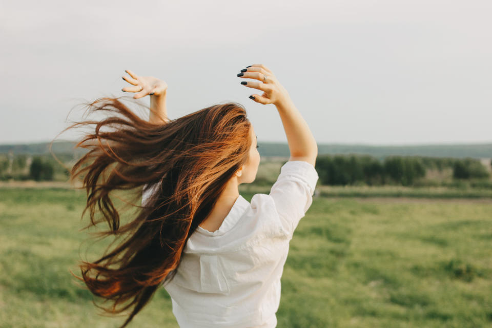 Close up portrait of beautiful long hair girl in white clothes in field, view from back. Sensitivity to nature concept