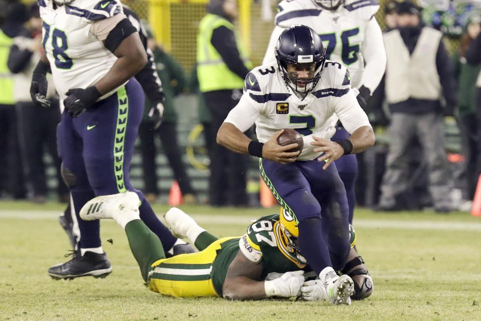 Seattle Seahawks' Russell Wilson gets away from Green Bay Packers' Kenny Clark during the first half of an NFL divisional playoff football game Sunday, Jan. 12, 2020, in Green Bay, Wis. (AP Photo/Darron Cummings)