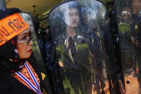 An anti-government protester stands in front of Air Force military personnel holding shields, after protesters broke into an air force base in Bangkok May 15, 2014. REUTERS/Damir Sagolj