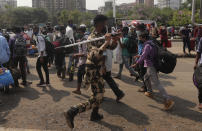 A police officer tries to control people waiting to catch trains at Lokmanya Tilak Terminus in Mumbai, India, Wednesday, April 14, 2021. India is experiencing its worst pandemic surge, with average daily infections exceeding 143,000 over the past week. (AP Photo/Rafiq Maqbool)