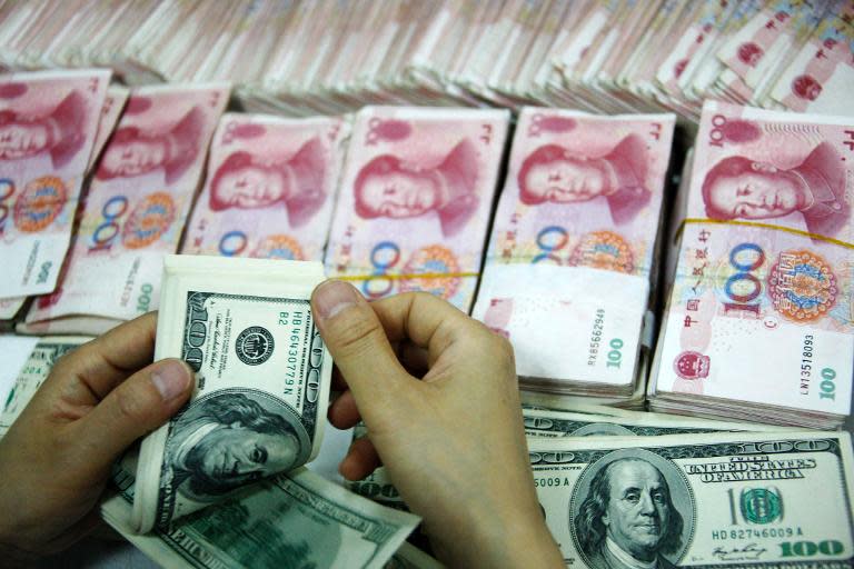 US dollar notes being counted next to stacks of Chinese 100 yuan (RMB) bank notes at a bank in Huaibei, in eastern China's Anhui province on September 24, 2013