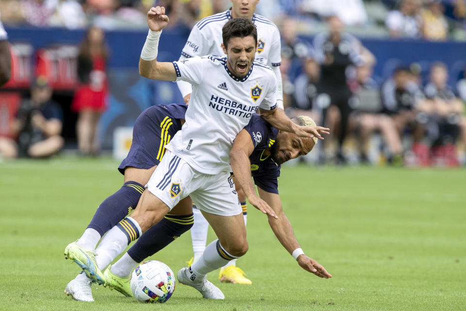 LA Galaxy midfielder Gaston Brugman, center, battles for the ball with Nashville SC midfielder Hany Mukhtar during the first half of an MLS playoff soccer match, in Carson, Calif., Saturday, Oct. 15, 2022. (AP Photo/Alex Gallardo)