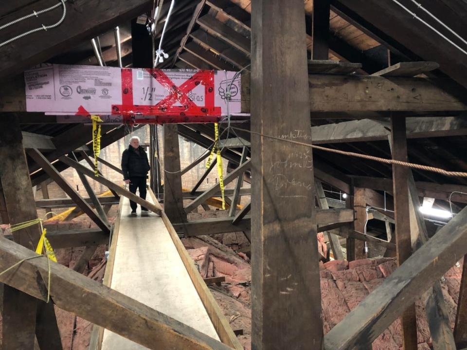 A number of safety upgrades have been made all over the church, including in the attic, which is pictured here. Paul Mullins, the restoration lead, is seen here walking on the brand new pathways that were installed in the attic. (Aastha Shetty/CBC - image credit)