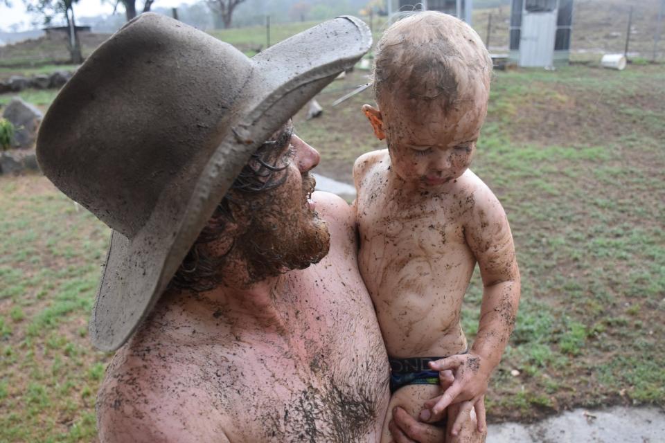 Wollomombi father and son Nick and Archie Saunders cover themselves in mud as rain falls.