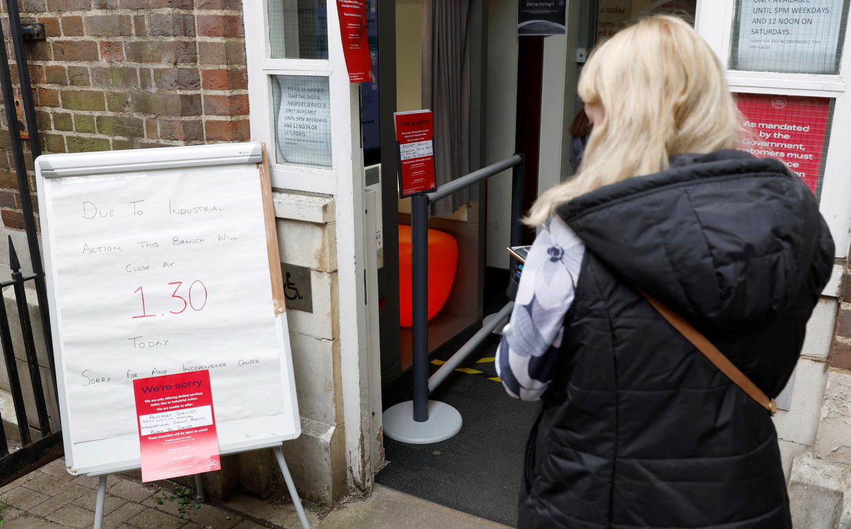 A woman walks past a sign informing customers of a Post Office branch closure due to industrial action, in St Albans, Britain, May 3, 2022.  REUTERS/Peter Cziborra