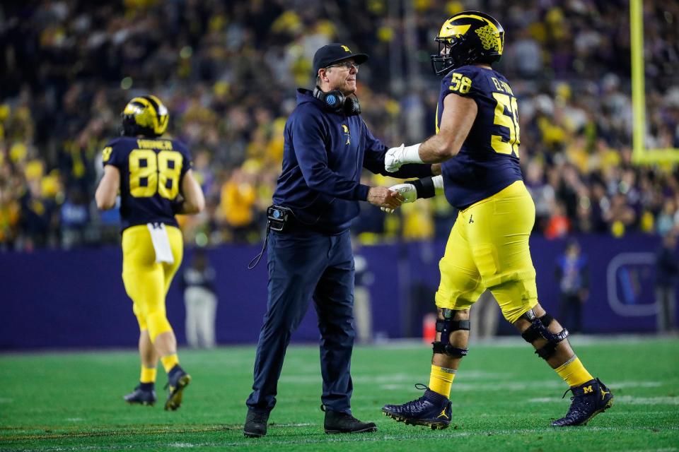 Michigan head coach Jim Harbaugh shakes hands with  offensive lineman Giovanni El-Hadi (58) after the Wolverines scored a touchdown against TCU during the second half at the Fiesta Bowl at State Farm Stadium in Glendale, Ariz. on Saturday, Dec. 31, 2022.