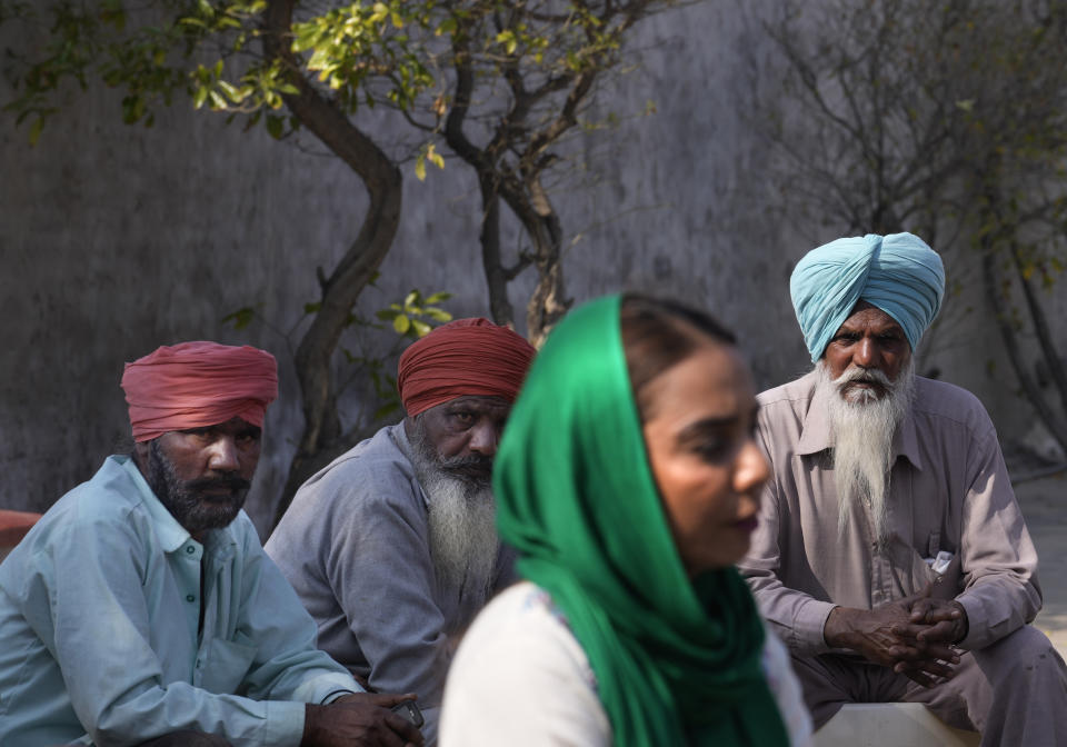 Villagers watch as Amandeep Kaur Dholewal, a candidate of the Sanyukt Samaj Morcha, the newly-minted political party of some farm unions that had spearheaded the farmer agitation, speaks during her election campaign, in village Derra Bassi, in Indian state of Punjab, Monday, Feb. 14, 2022. India's Punjab state will cast ballots on Sunday that will reflect whether Indian Prime Minister Narendra Modi's ruling Bharatiya Janata Party has been able to neutralize the resentment of Sikh farmers by repealing the contentious farm laws that led to year-long protests. (AP Photo/Manish Swarup)