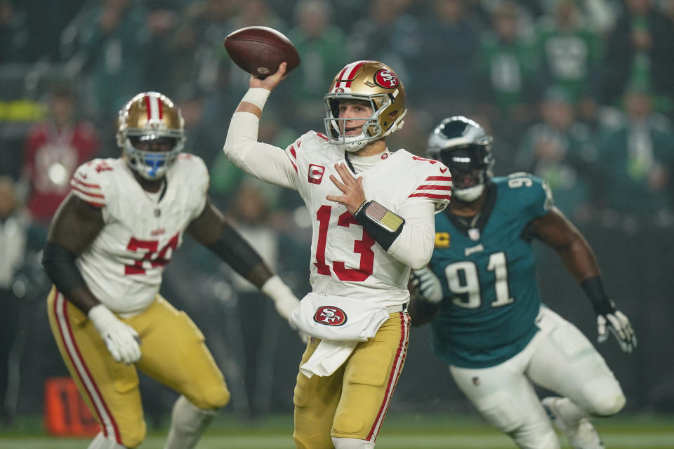 San Francisco 49ers quarterback Brock Purdy (13) attempts a pass as Philadelphia Eagles defensive tackle Fletcher Cox (91) chases after him during the first half of an NFL football game, Sunday, Dec. 3, 2023, in Philadelphia. San Francisco's Spencer Burford (74) looks on. (AP Photo/Chris Szagola)