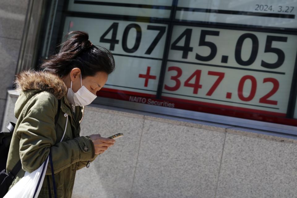 A person walks in front of an electronic stock board showing Japan's Nikkei 225 index at a securities firm Wednesday, March 27, 2024, in Tokyo. Asian shares were mixed on Wednesday after Wall Street slipped a bit further from its record highs. (AP Photo/Eugene Hoshiko)