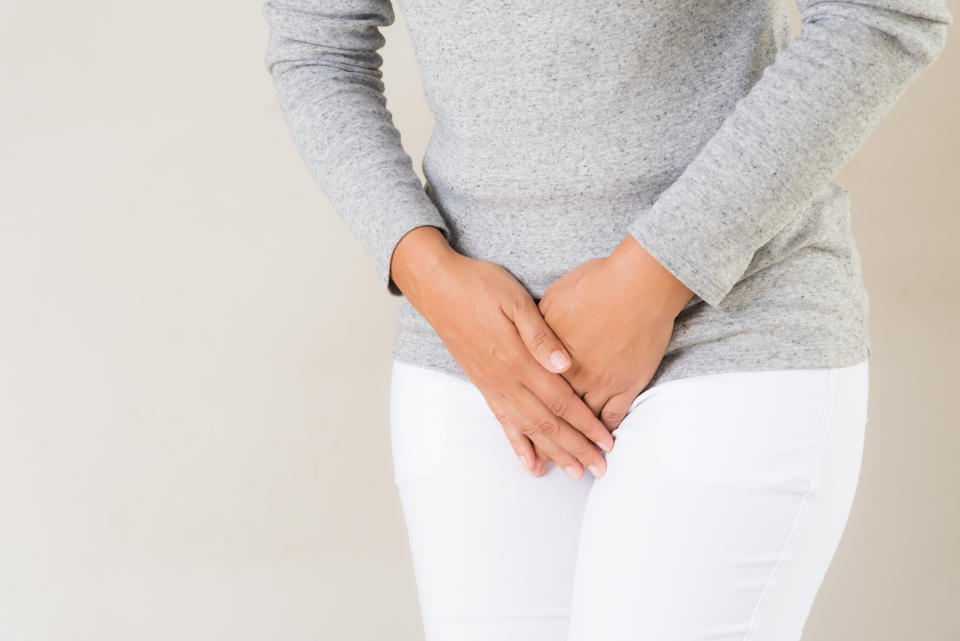 Young woman having painful stomachache with hands holding pressing her crotch lower abdomen. Medical or gynecological problems, healthcare concept