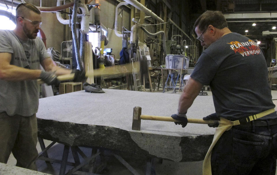 FILE- In this Jan. 8, 2019 file photo, stone cutters Evan Ladd, left, and Andy Hebert cut a piece of granite at Rock of Ages in Barre, Vt., for use in the 9/11 Memorial Glade in New York. Set in a glade of trees at the Nationals September 11 Memorial & Museum, the granite slabs recognize an initially unseen toll of the 2001 terror attacks: firefighters, police and others who died or fell ill after exposure to toxins unleashed in the wreckage. (AP Photo/Lisa Rathke, File)