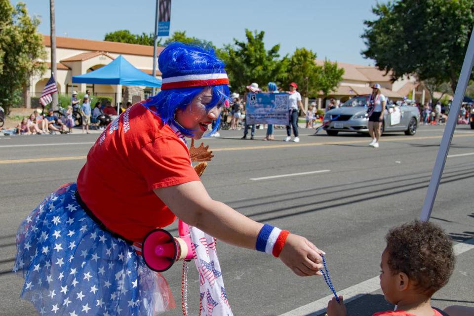 Terry Gough, past regent of the Rancho Cordova Moose Lodge, hands out beaded necklaces at the Million Dreams Fourth of July Parade on Tuesday, July 4, 2023. The parade went down Coloma Road and was part of a 2-day festival with carnival rides, music, fireworks and drone shows at Rancho Cordova’s Hagan Community Park.