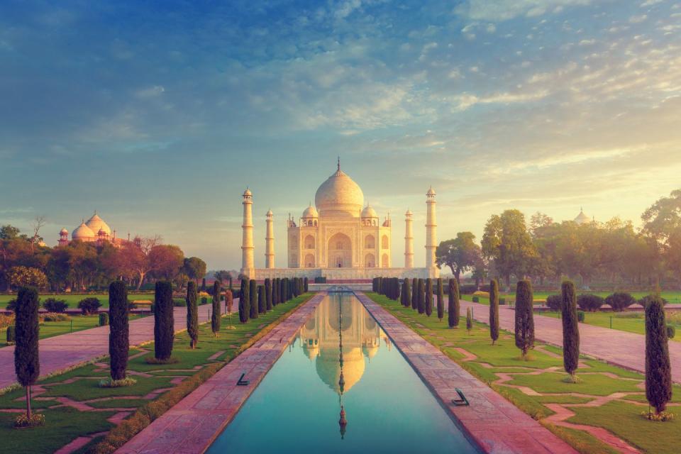 a large building with a dome and a pool of water in front with taj mahal in the background