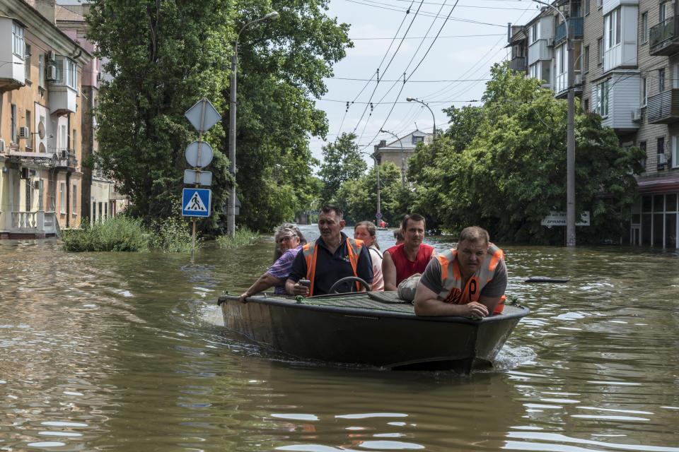 Residentes en tablas de surf maniobran a través de un vecindario inundado en Jersón, Ucrania, el 7 de junio de 2023. (Mauricio Lima/The New York Times)