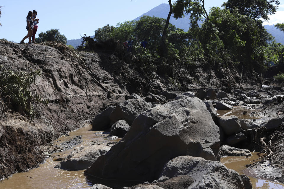 Una mujer toma fotos el viernes 30 de octubre de 2020 de un área destruida durante un deslizamiento de tierra, en Nejapa, El Salvador. (AP Foto/Salvador Meléndez)