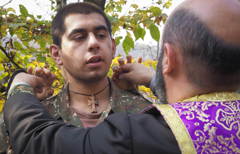 Priest Aristakes Hovhannisyan places a crucifix on an ethnic Armenian soldier during a baptism ceremony in a military camp near the front line during a military conflict in separatist region of Nagorno-Karabakh, Monday, Nov. 2, 2020. Fighting over the separatist territory of Nagorno-Karabakh entered sixth week on Sunday, with Armenian and Azerbaijani forces blaming each other for new attacks. (AP Photo)