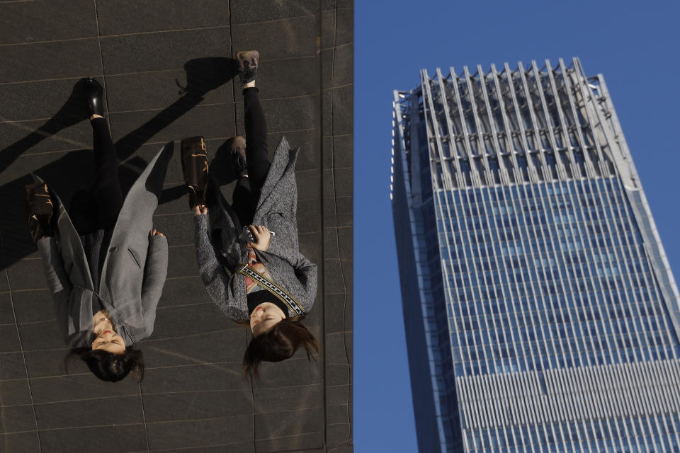 In this March 6, 2019, photo, women are reflected on silver panels of the French luxury brand Louis Vuitton flagship store at the Central Business District in Beijing. China will bar government authorities from demanding overseas companies hand over technology secrets in exchange for market share, a top economic official said Wednesday, addressing a key complaint at the heart of the current China-U.S. trade dispute. (AP Photo/Andy Wong, File)