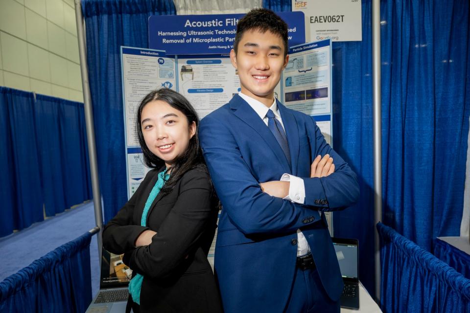 Victoria Ou and Justin Huang stand back to back wearing a black and blue suit