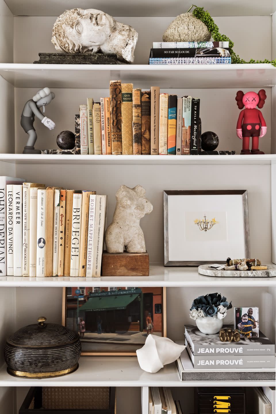 a white shelf with books and figurines on it