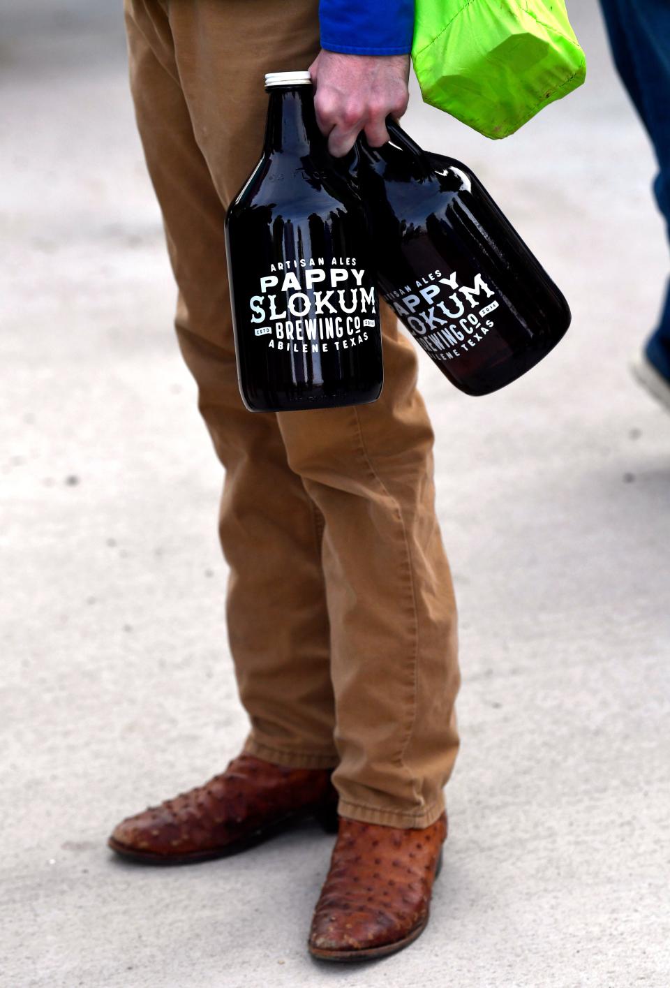 A customer waits in a line that went out to the street, holding two growlers at Pappy Slokum's.