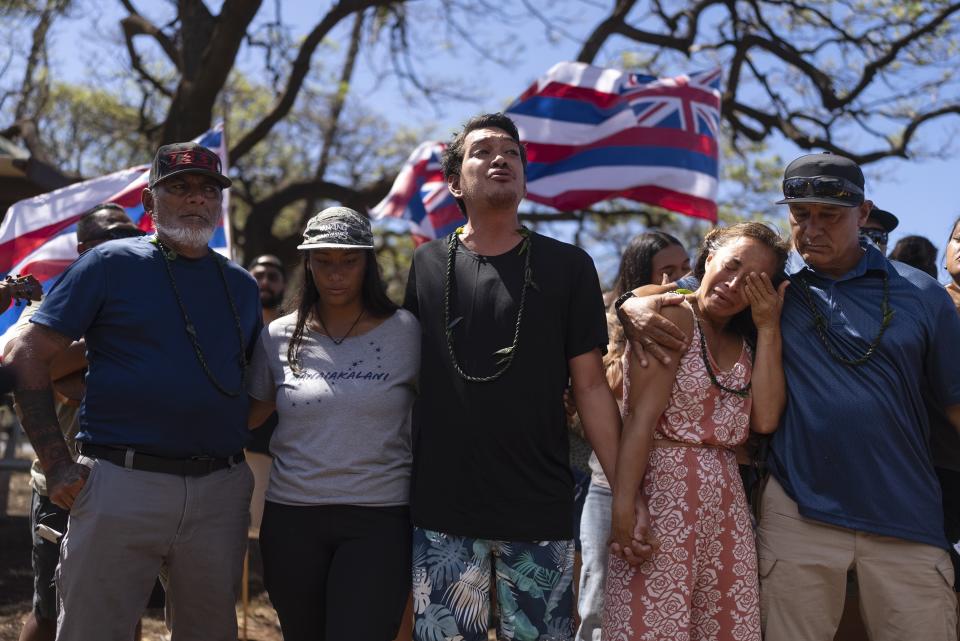 Community organizer Tiare Lawrence, second from right, is comforted by Archie Kalepa as they sing a song during a news conference with Lahaina, Hawaii, residents affected by a deadly wildfire in Lahaina, Hawaii, Aug. 18, 2023. (AP Photo/Jae C. Hong)