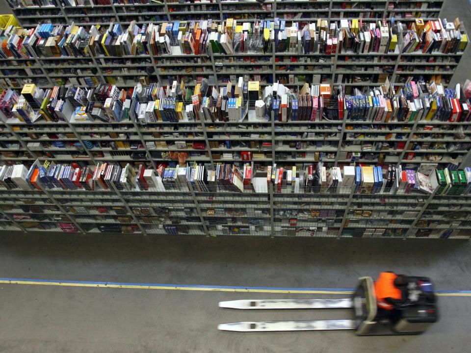 Amazon warehouse employee drives forklift among shelves