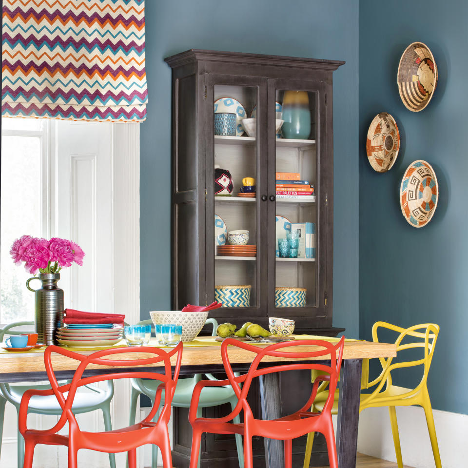 Blue dining room with glass fronted dresser and patterned window blinds