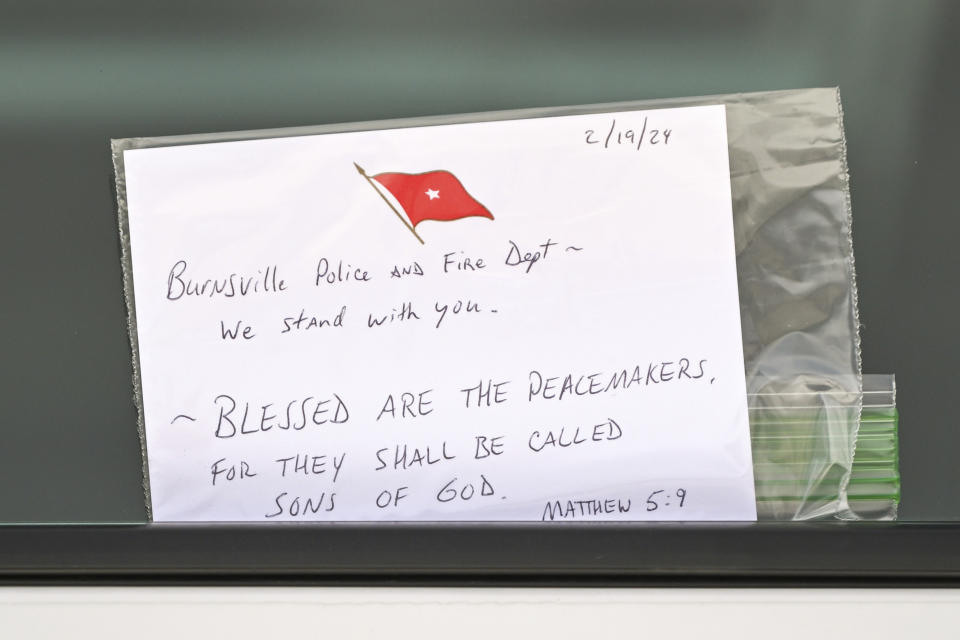 A note is left tucked in a window of a squad car that was one of three memorials in front of the Burnsville Police Department in Burnsville, Minn., Monday, Feb. 19, 2024. Two police officers and a firefighter who responded to a domestic situation at a suburban Minneapolis home were killed early Sunday during a standoff by a heavily armed man who shot at police from the home where seven children were also inside. (Craig Lassig/Pioneer Press via AP)