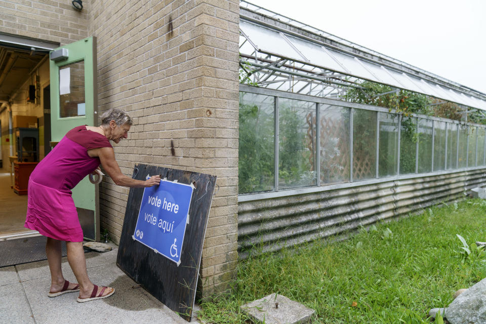 Poll supervisor Debbie Schimberg puts out a sign marking the entrance for voters for the state's primary election at the Roger Williams Park Botanical Center in Providence, R.I., Tuesday, Sept. 13, 2022. (AP Photo/David Goldman)