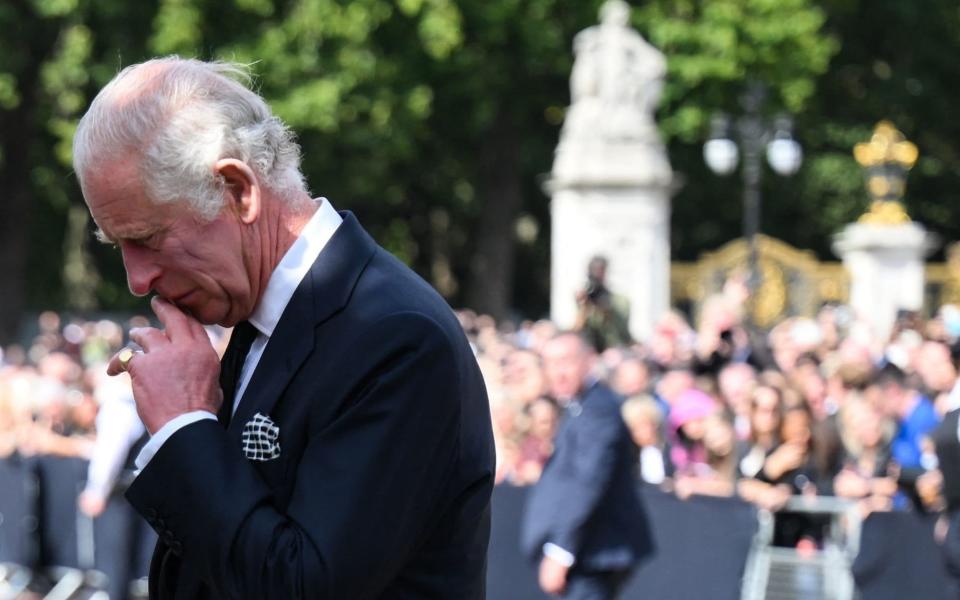 The King takes a moment to look at flowers, cards and tributes left outside Buckingham Palace - DANIEL LEAL/AFP via Getty Images