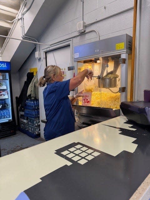 Adirondack Bank Center concession stand employee Cindy Testa fills a carton of popcorn.