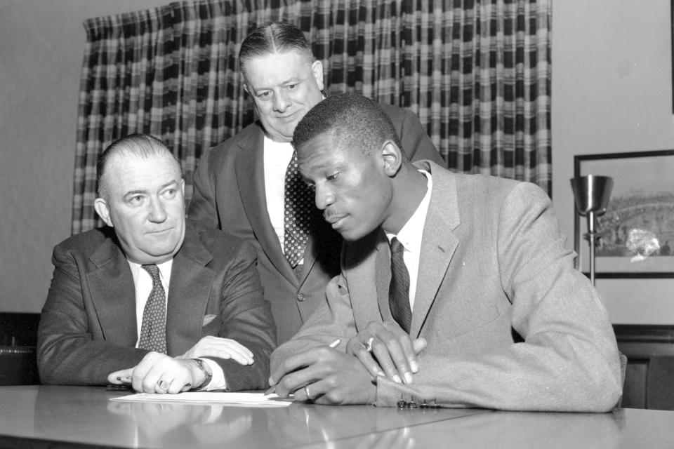 FILE - In this Dec. 19, 1956, file photo, basketball player Bill Russell, right, signs the contract with the Boston Celtics of the NBA at Boston Garden in Boston, Mass. Seated at left is Celtics co-owner and president Walter Brown, and standing behind him is co-owner Lou Pieri of Providence, R.I. (AP Photo/File)