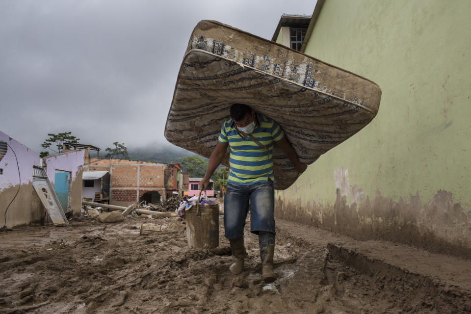 A displaced resident carries a mattress and bucket of supplies after a landslide in Mocoa, Colombia, in 2017.  (Nicolo Filippo Rosso / Bloomberg via Getty Images)