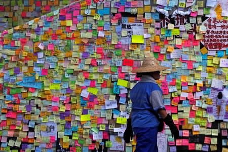 A worker walks past post-it notes scribbled with messages, left behind by protesters on the walls of the Legislative Council, a day after protesters broke into the building, in Hong Kong