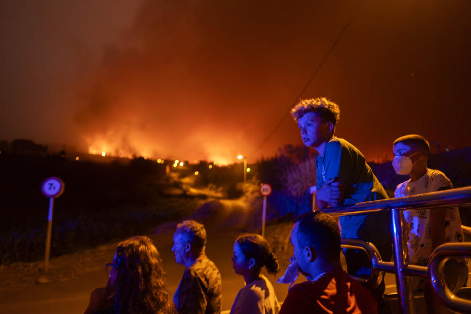 Local residents try to reach their houses in Benijos village as police block the area as fire advances in La Orotava in Tenerife, Canary Islands, Spain on Saturday, Aug. 19, 2023. (AP Photo/Arturo Rodriguez)