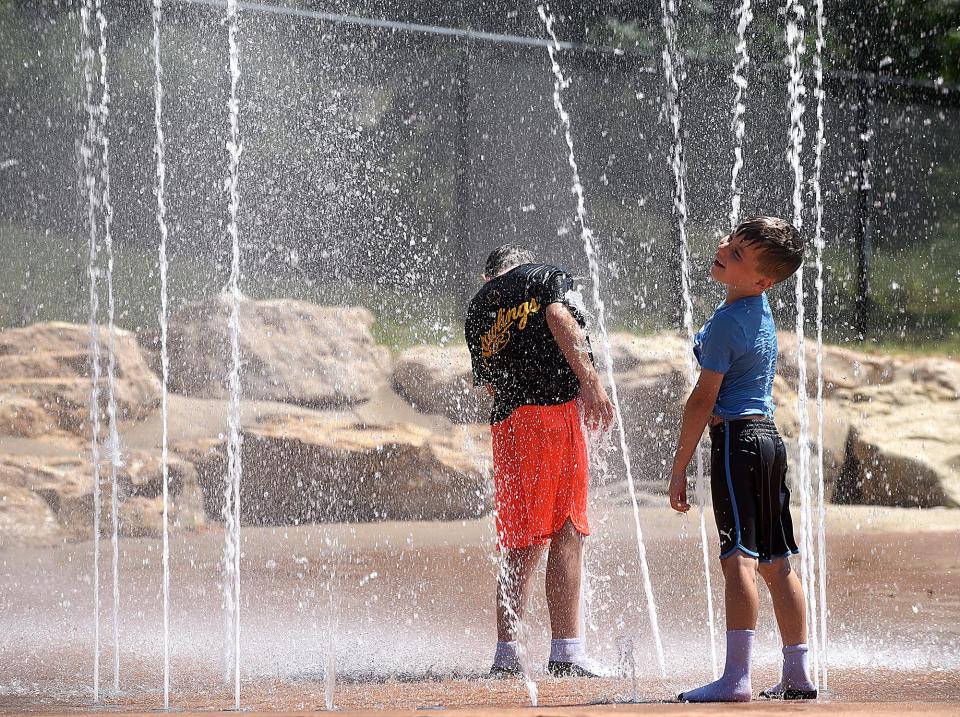 Henry Koonse, 9, left, and his brother Charles, 6, play in the Stephens Lake Park sprayground on Tuesday.