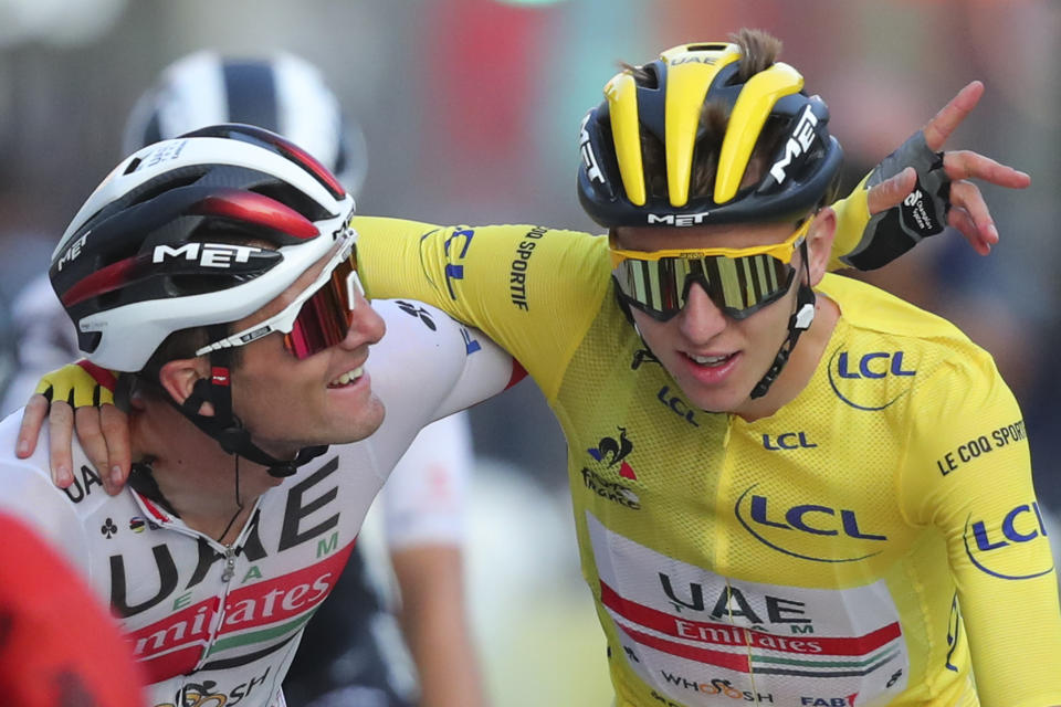 El campeón del Tour de Francia Tadej Pogacar, con el maillot amarillo, es felicitado por un compañero al cruzar la meta de la última etapa en París, el domingo 20 de septiembre de 2020. (AP Foto/Thibault Camus, Pool)