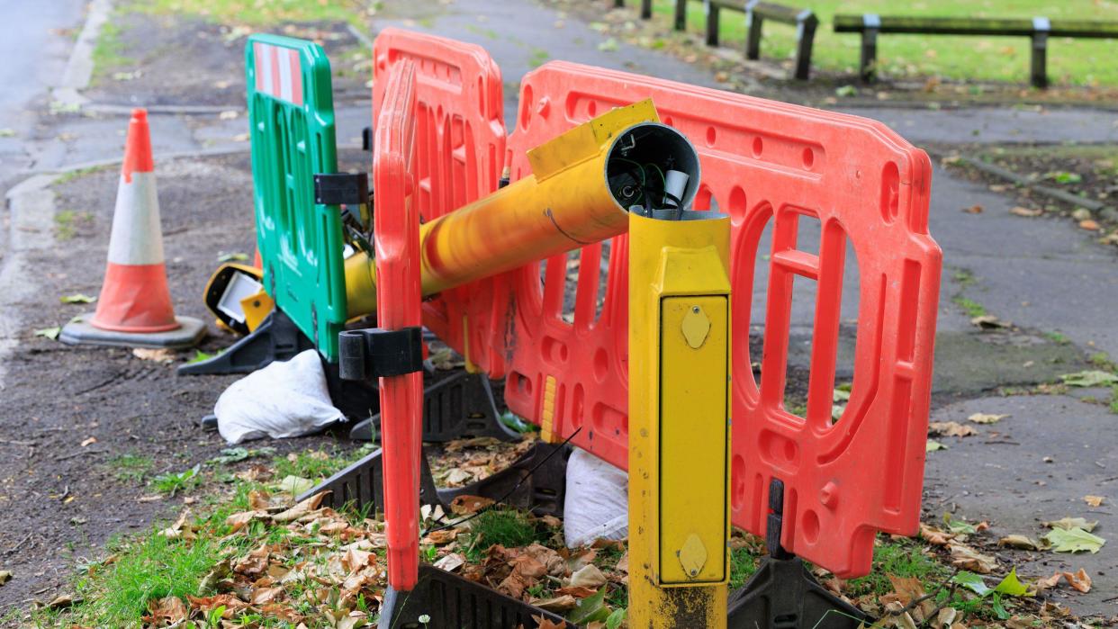 A speed camera pole is sawn in two, with the majority of the yellow pole resting on the ground
