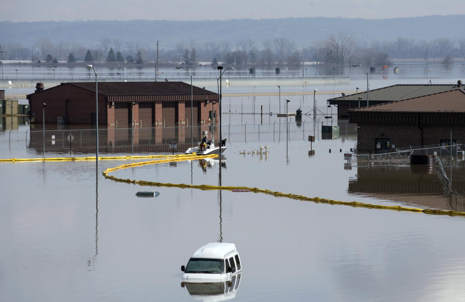 In this March 18, 2019 photo released by the U.S. Air Force, environmental restoration employees deploy a containment boom from a boat on Offutt Air Force Base in Neb., as a precautionary measure for possible fuel leaks in the flooded area. Surging unexpectedly strong and up to 7 feet high, the Missouri River floodwaters that poured on to much the Nebraska air base that houses the U.S. Strategic Command overwhelmed the frantic sandbagging by troops and their scramble to save sensitive equipment, munitions and aircraft. (Delanie Stafford, The U.S. Air Force via AP)