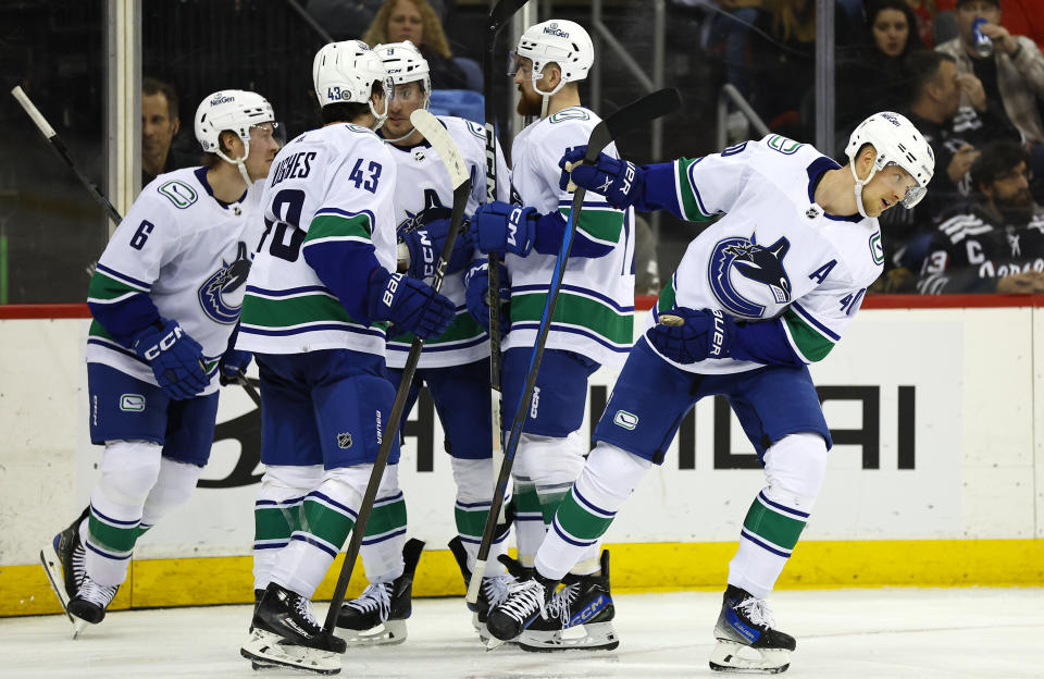 Vancouver Canucks center Elias Pettersson, right, heads to the bench after scoring against the New Jersey Devils during the third period of an NHL hockey game, Saturday, Jan. 6, 2024, in Newark, N.J. (AP Photo/Noah K. Murray)