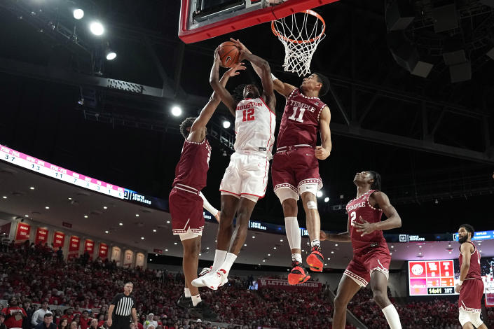 Houston's Tramon Mark (12) goes up for a shot as Temple's Nick Jourdain (11) and Zach Hicks, left, defend during the first half of an NCAA college basketball game Sunday, Jan. 22, 2023, in Houston. (AP Photo/David J. Phillip)