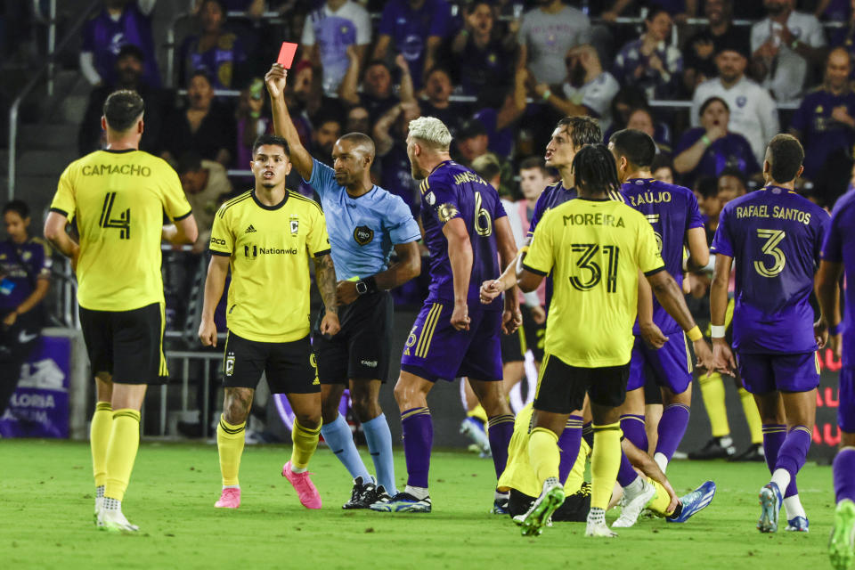 Referee Jon Fresnon pulls red card against Orlando City defender Rodrigo Schlegel (in front of #31) as team mate Orlando City defender Robin Jansson (6) agrees as they play Columbus Crew during the second half of an MLS soccer playoff match, Saturday, Nov. 25, 2023, in Orlando, Fla. (AP Photo/Kevin Kolczynski)