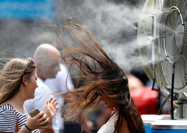 <p>Während der Australian Open in Melbourne kühlt sich eine Besucherin an einem Ventilator ab, der Wasser versprüht. (Bild: Kin Cheung/AP) </p>