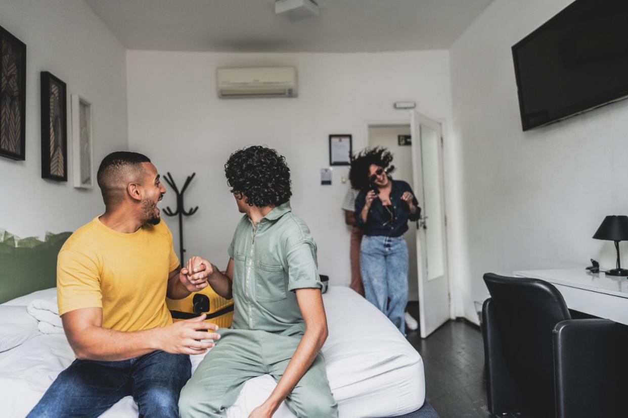 couple and friend inside a hotel room greeting each other