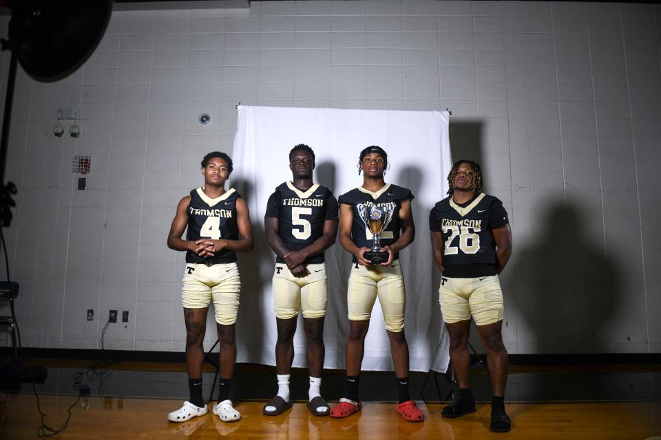 [From left] Thomson defensive back Storm Hunt (4), quarterback Jahkiaus Jones (5), defensive back Jamere Roberts (12), and running back Anthony Jeffery (26) pose for a portrait with the 2023 state championship trophy at Thomson High School on July , 2023.
